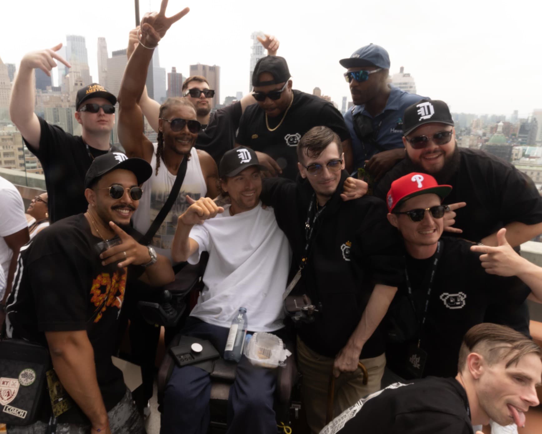 Crash (CrashMetaX) surrounded by friends on a New York rooftop with the skyline behind them